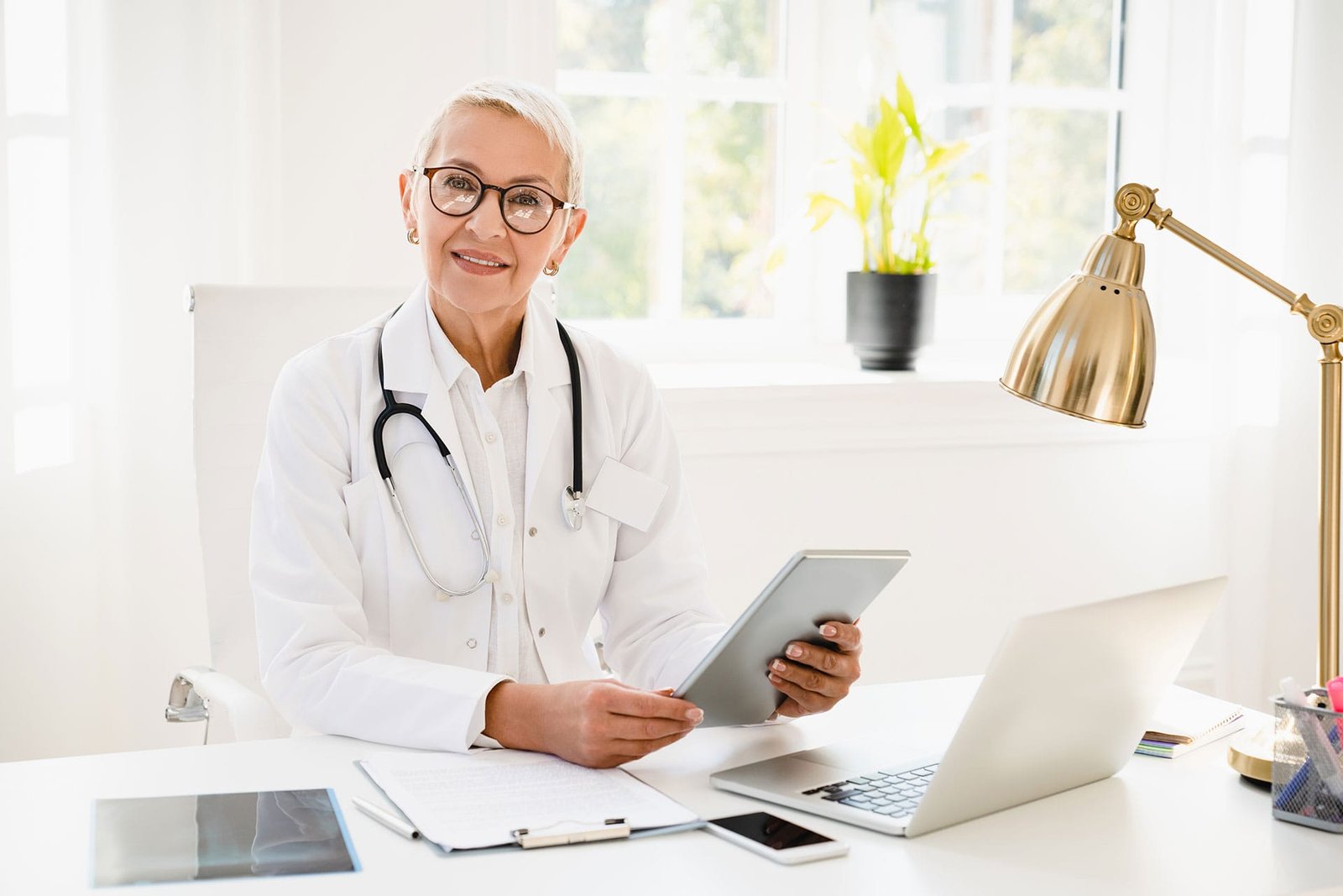 Senior Female Doctor In White Coat Using Digital T 2021 12 09 20 04 30 X4gbeva.jpg